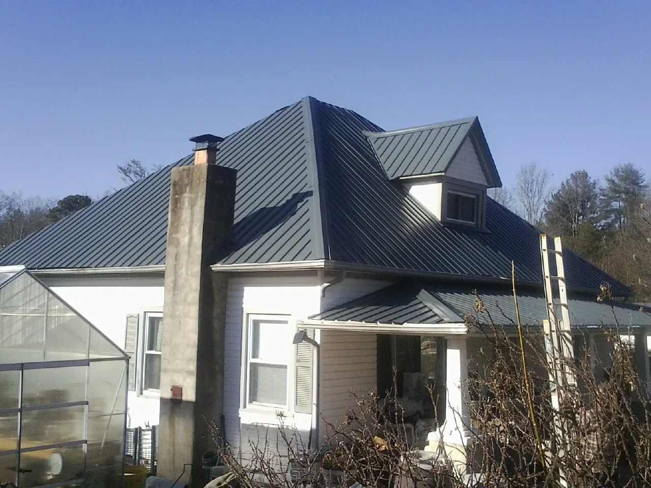 Dark blue standing seam metal roof on a white farmhouse with dormer — Slate & Tile Roof Repair by Roofing Brothers in Connelly Springs