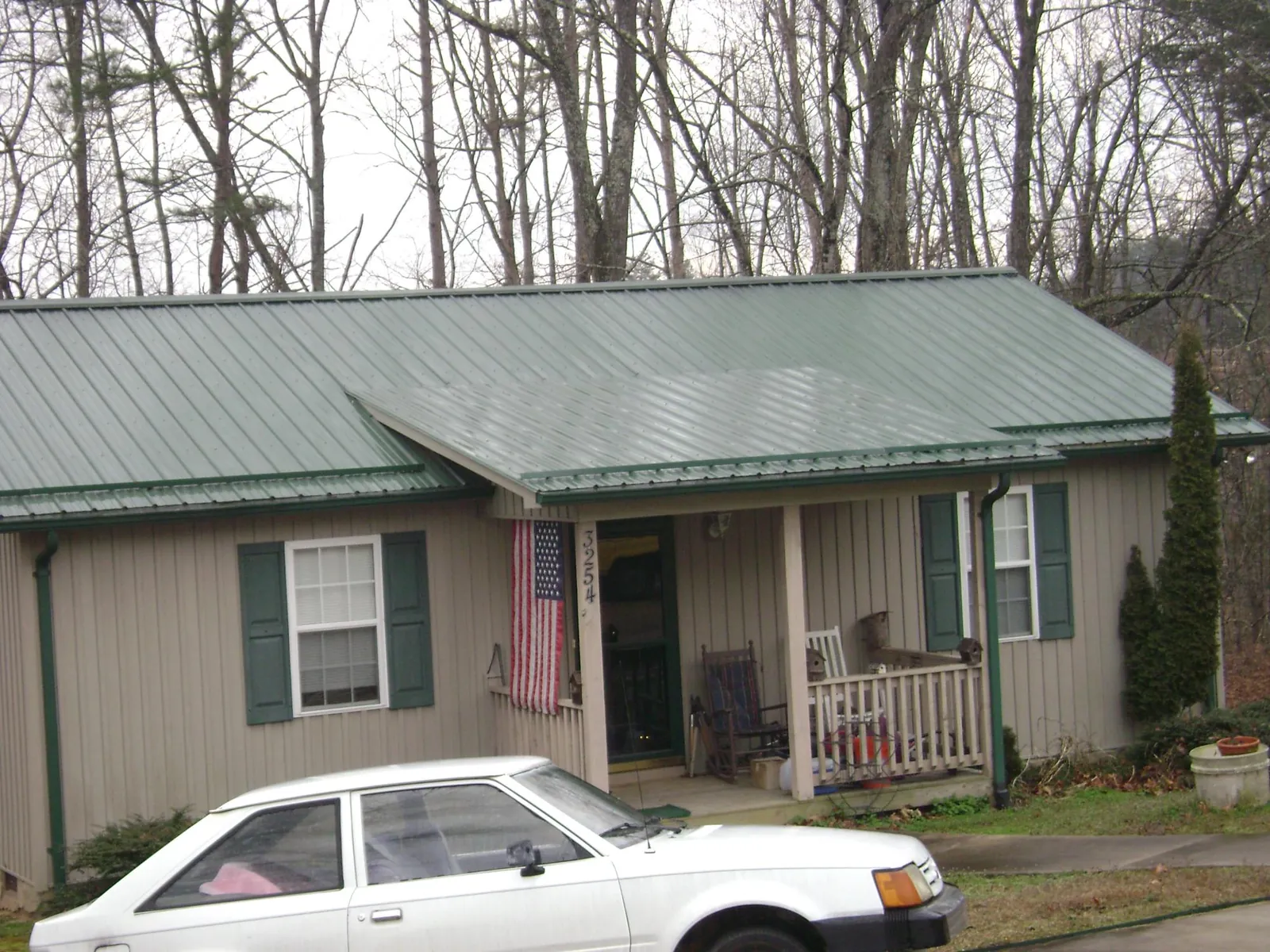Green metal roof and front porch on a tan sided cottage in Connelly Springs