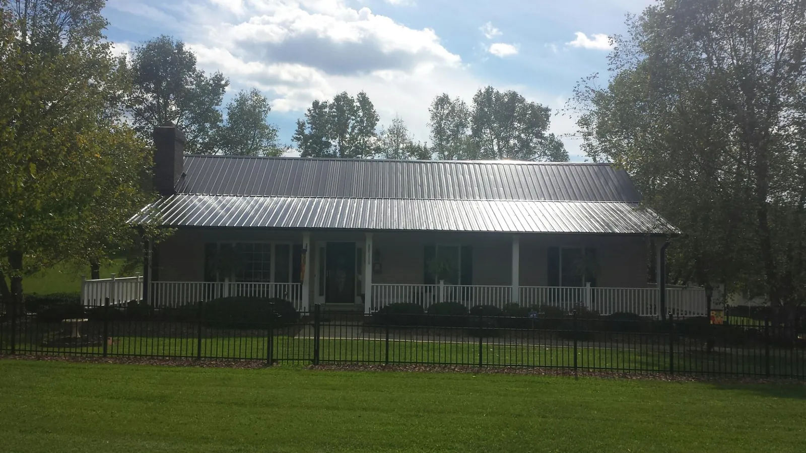 Gray metal roof on a brick ranch with a full width front porch — Gutter Guard Installation work by our crew in Connelly Springs