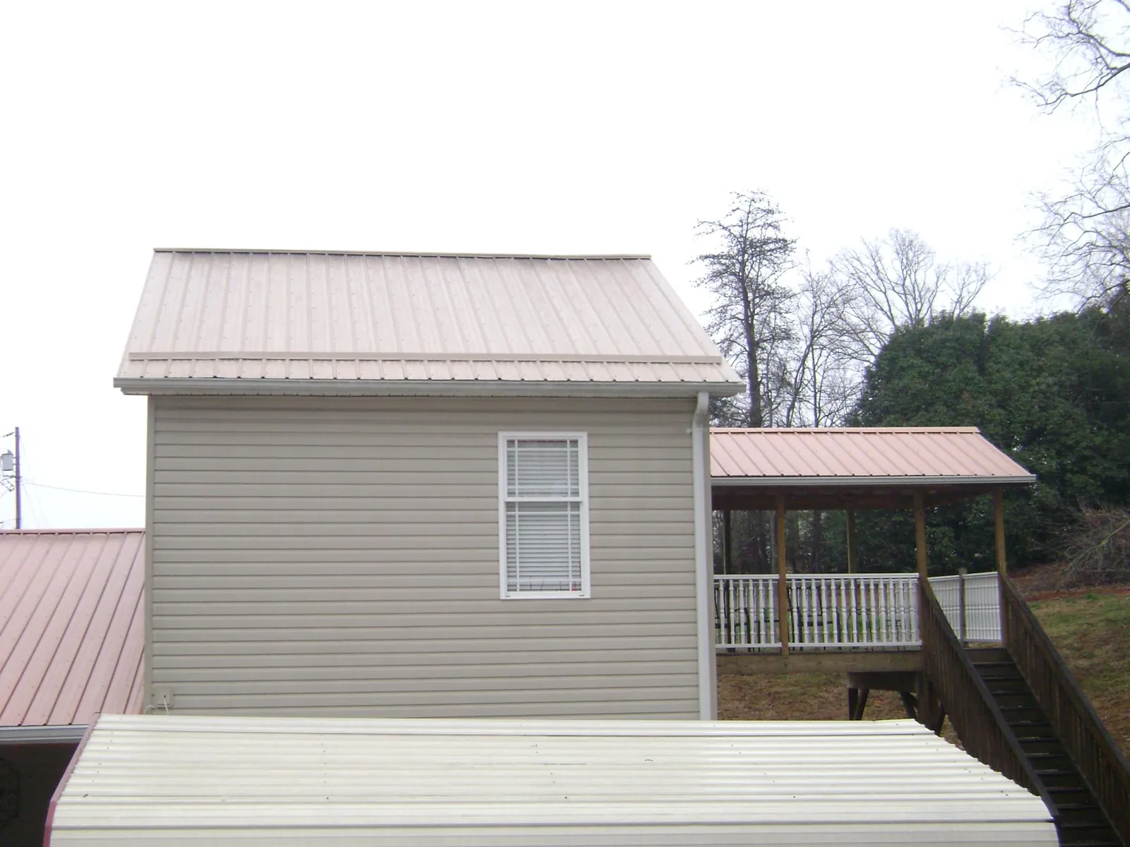 Tan metal roofs on a two story addition and attached porch, from a Roof Replacement job in Connelly Springs