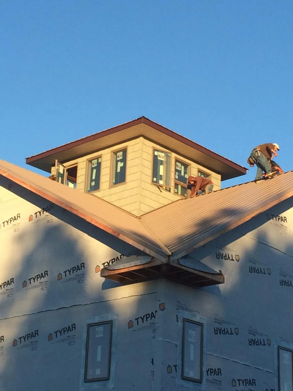 Roofers working around a rooftop cupola on a new metal roof at sunset — Roof Waterproofing in Connelly Springs by Roofing Brothers